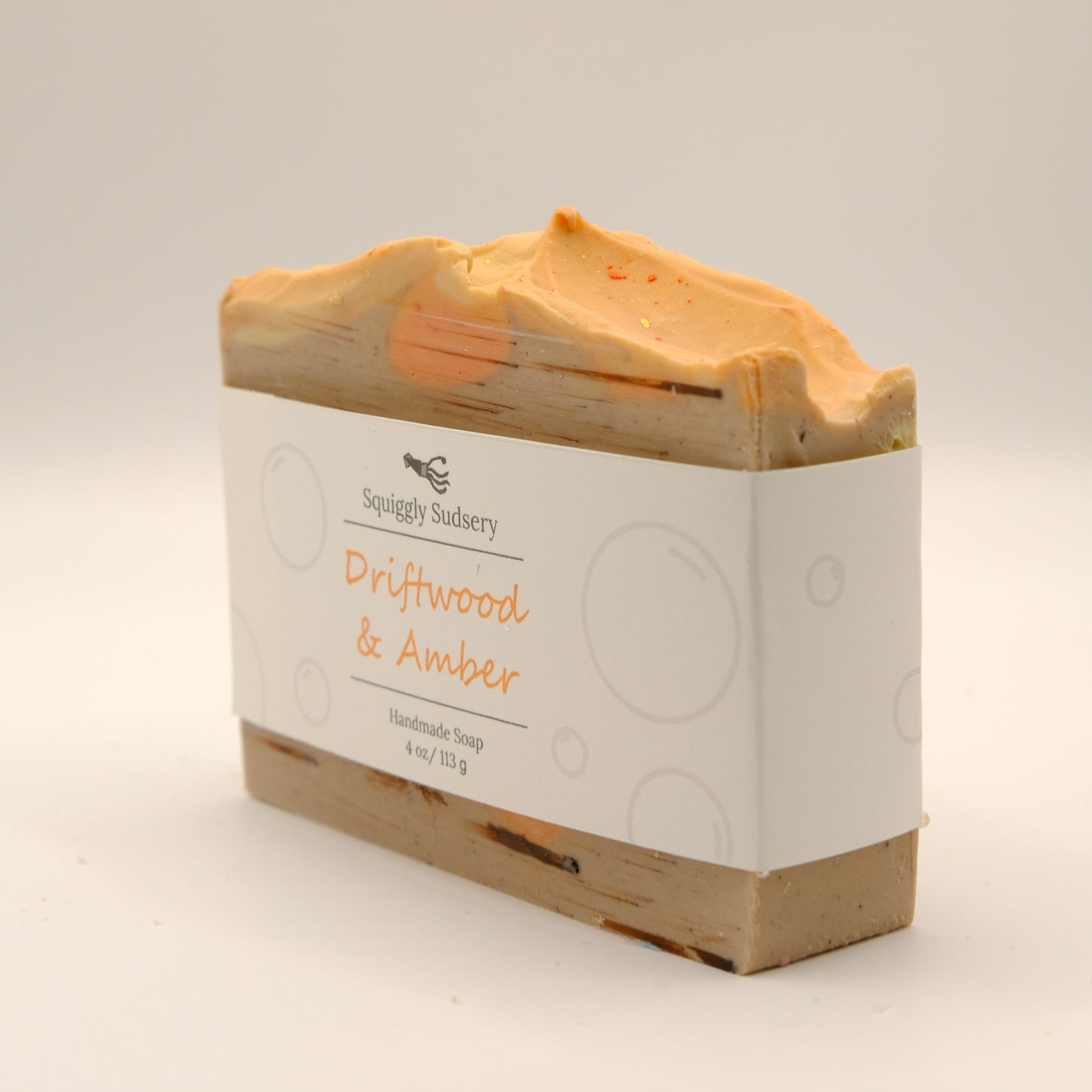 Bar of soap with a textured top and 'Squiggly Sudsery' branding on a light background
