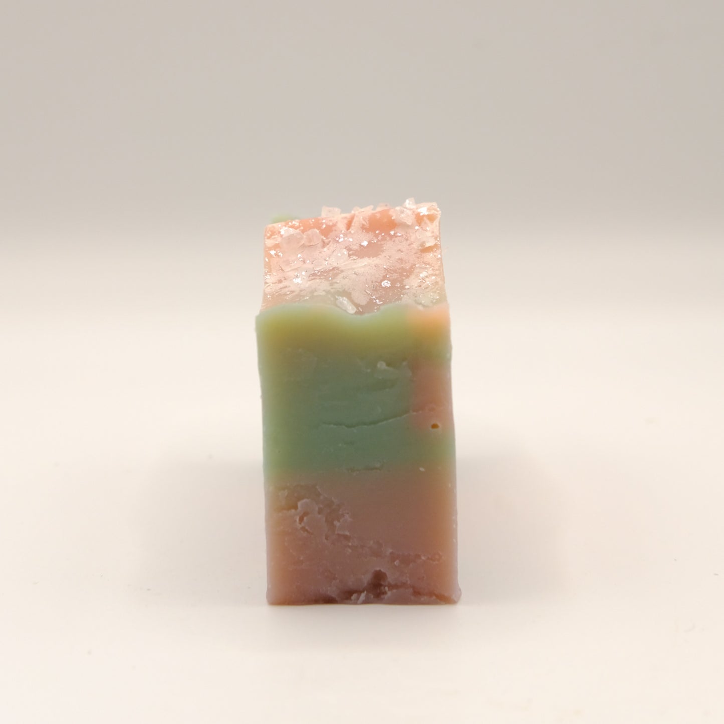Bar of soap with a gradient from green to pink on a light background