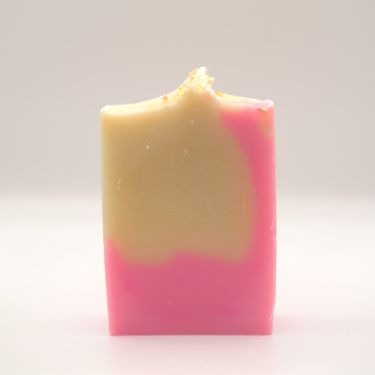 Two-tone pink and yellow bar of soap n a white background