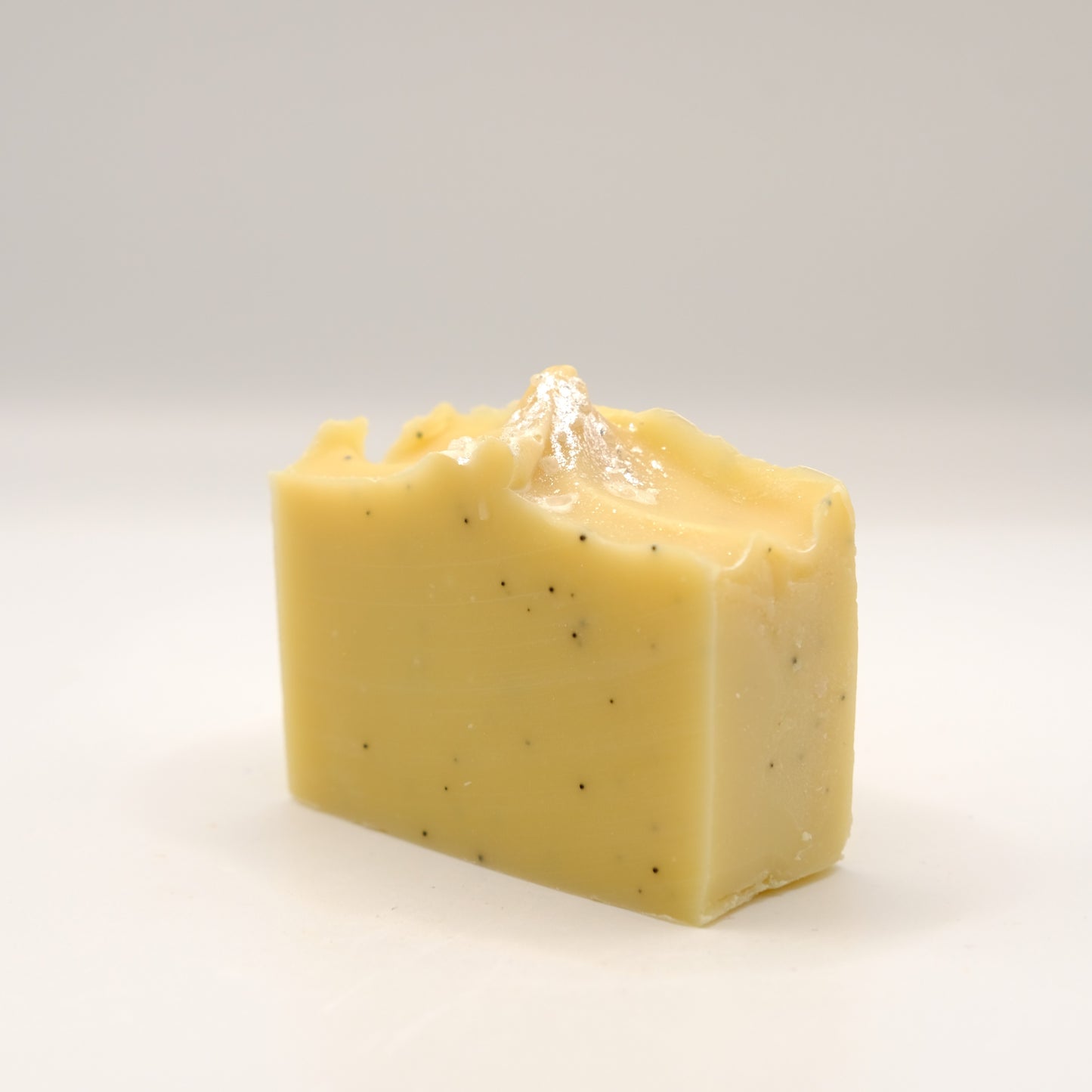 Yellow soap bar with specks on a white background