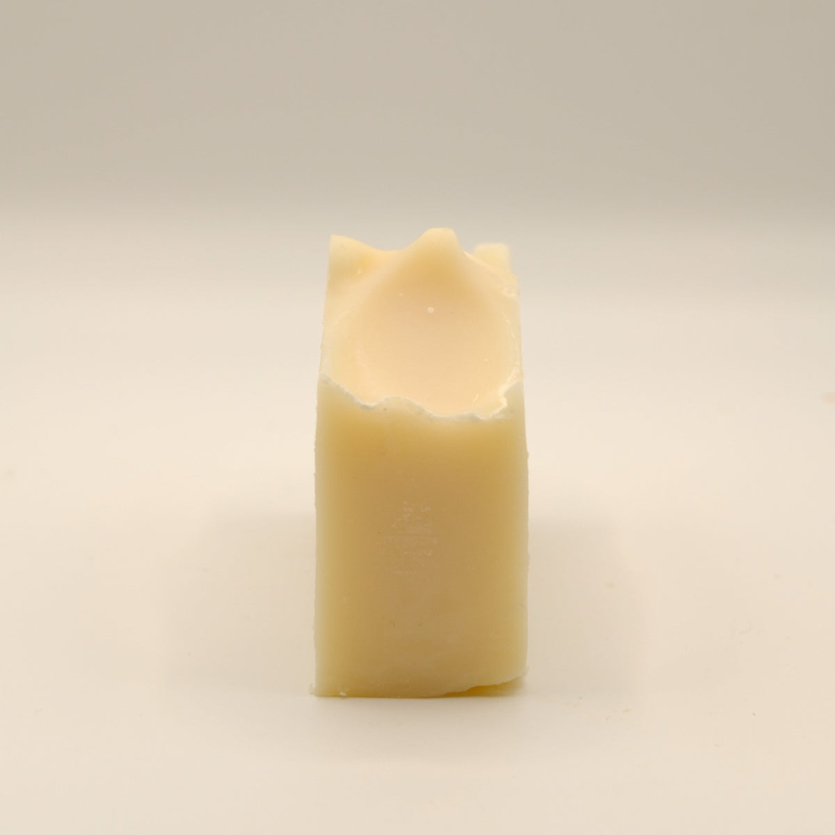 Beige bar of soap with a texture top on a light surface