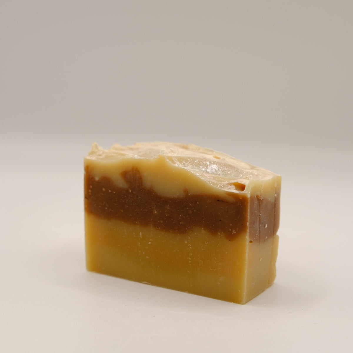 Bar of soap with brown and beige coloration on a light gray background