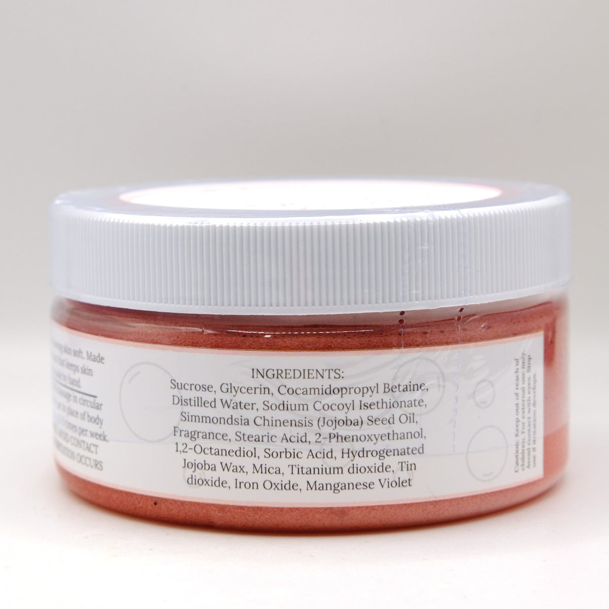 Jar of red sugar scrub with a white lid on a light gray background