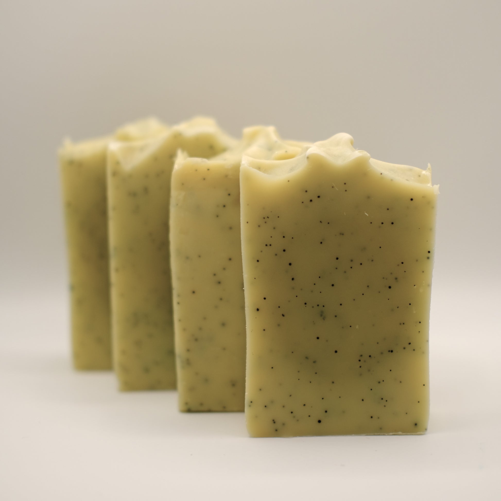 Four bars of speckled yellow soap on a light gray background