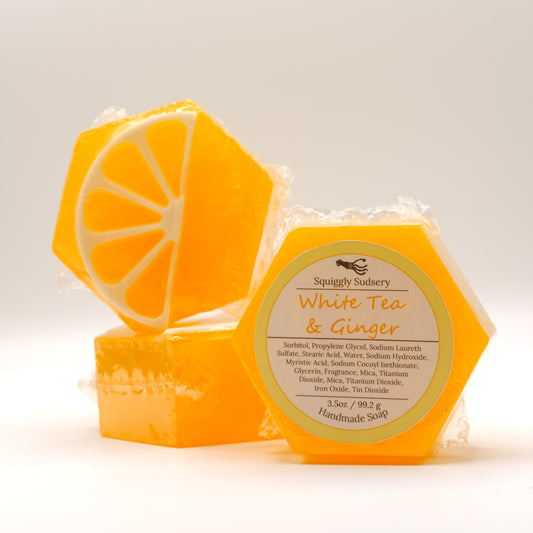 Hexagonal orange soap with an orange slice design and a label on a light background