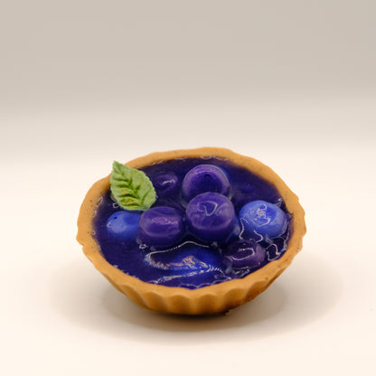 Small tart-shaped soap with blue fruit filling and a mint leaf design on a beige background
