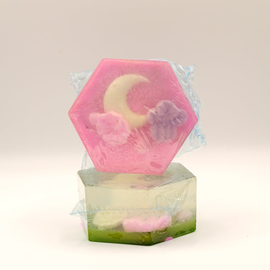 Hexagonal soap with a floral design in a clear plastic wrap on a light beige background