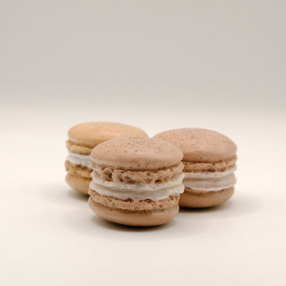 Three macaron-shaped soap bars with white filling on a light beige background