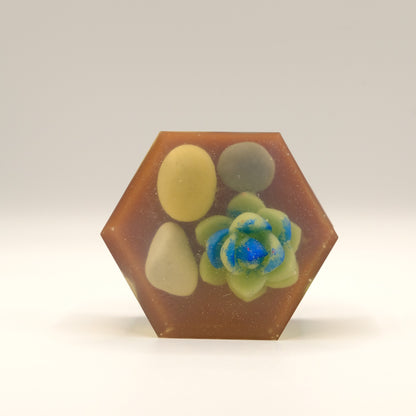 Hexagonal soap bar with embedded stones and succulent on a white background