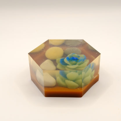 Hexagonal soap bar with embedded stones and succulent-like design on a white background