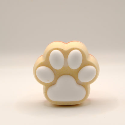 Yellow, orange and white soap bar with a paw print design on a light gray background