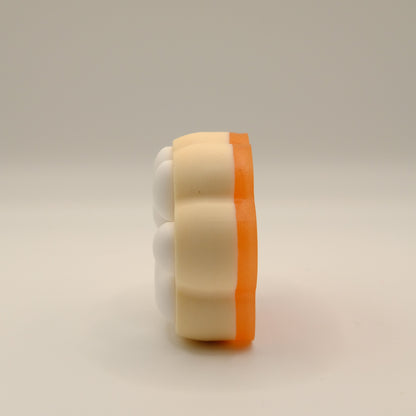 Yellow, orange and white soap bar with a paw print design on a light gray background