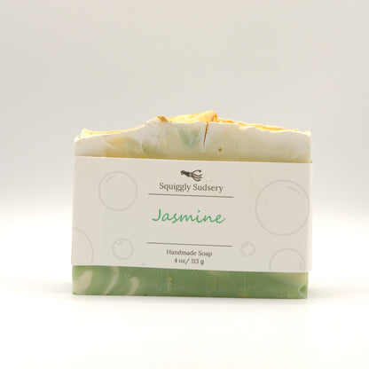 Handmade soap bar with 'Squiggly Sudsery' branding and 'Jasmine' scent on a white background