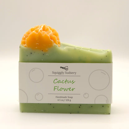 Green and orange handmade soap bar with cactus flower design and speckles on a white background