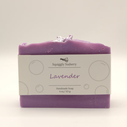 Purple soap bar with 'Squiggly Sudsery' branding on a light gray background