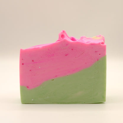 Two-toned soap bar with green on the bottom and pink top with a textured top on a light background