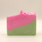 Two-toned soap bar with green on the bottom and pink top with a textured top on a light background