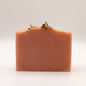 Pink bar of soap with natural elements and gold accents on a white background