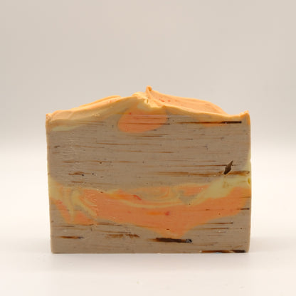 Bar of soap with a brown-orange-yellow marbled design and textured top on a white background