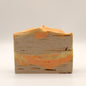 Bar of soap with a brown-orange-yellow marbled design and textured top on a white background