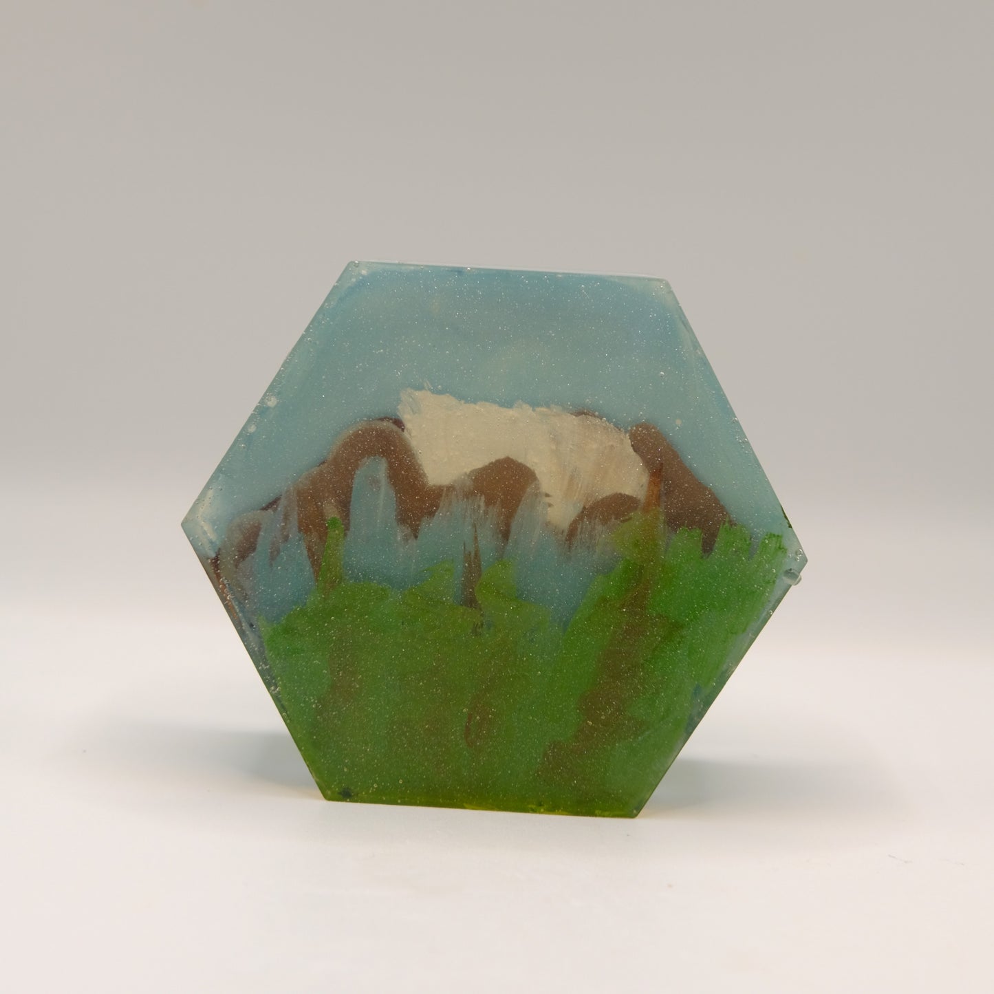 Hexagonal soap bar with mountain landscape design on a white background