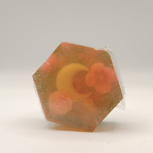 Hexagonal soap bar with visible flower and moon shaped pieces on a white background