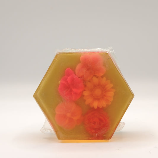 Packaged hexagonal soap bar with red and orange flowers on a white background
