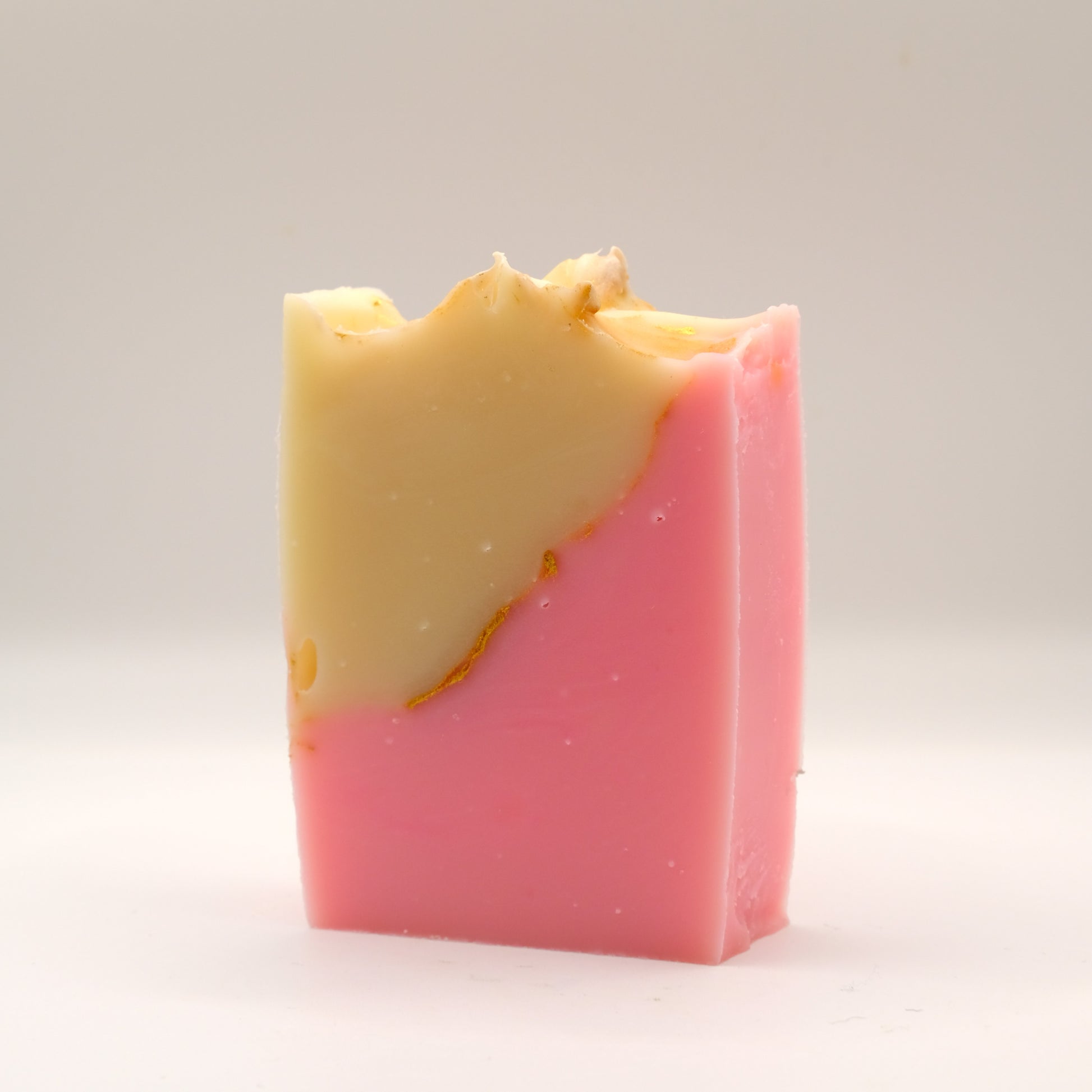 Two-tone beige and pink soap bar with a textured top on a light gray background