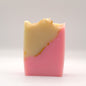 Two-tone pink and yellow soap bar with a textured top and gold accents on a white background