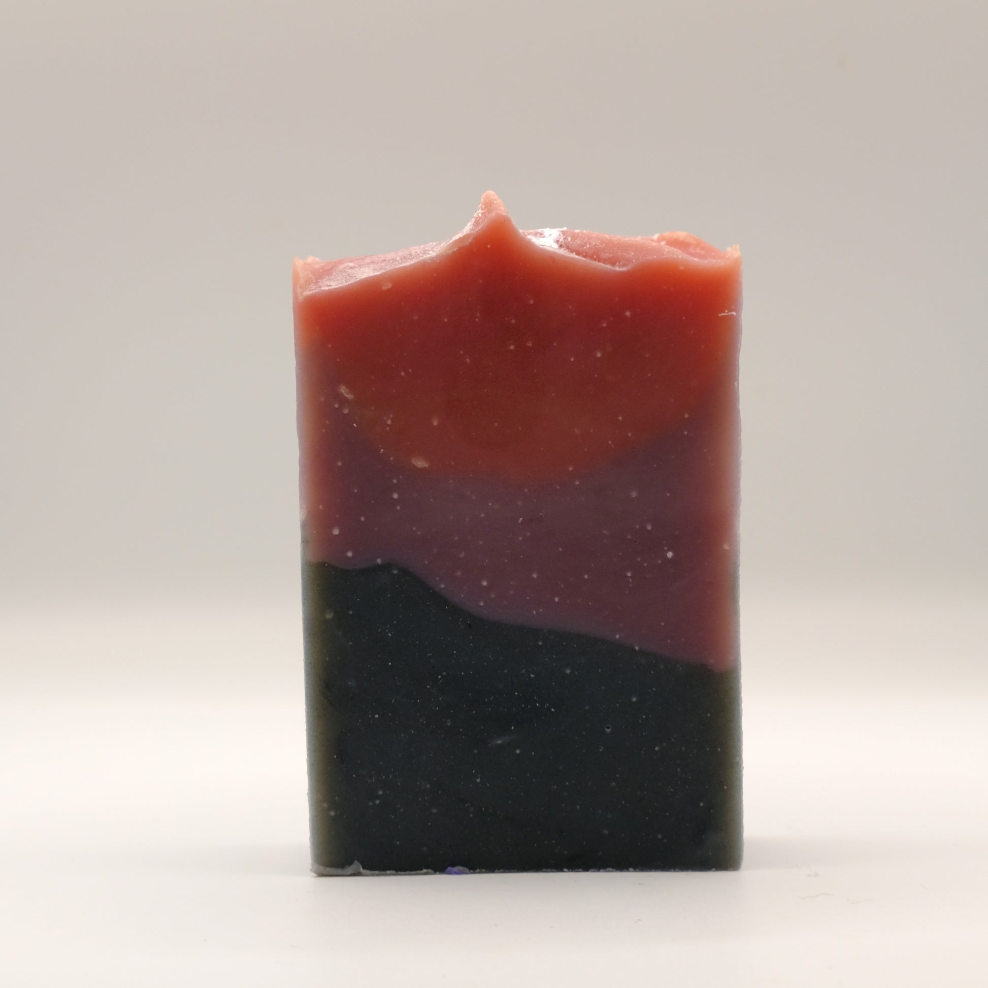 Three layered soap bar with black purple and red on a white background