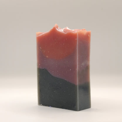 Three-layered soap bar with red, purple, and black layers on a white background