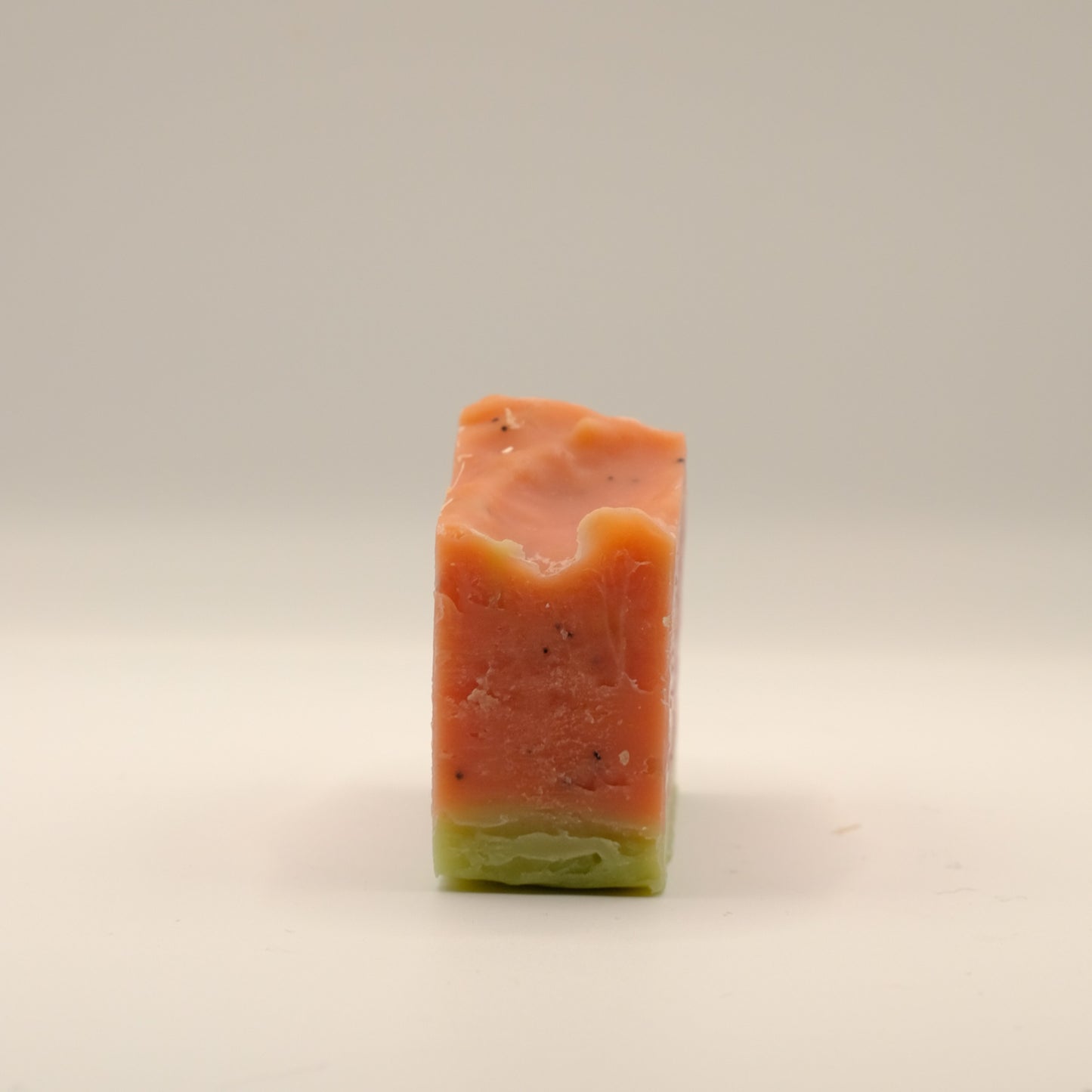 Rectangular bar of soap with a gradient from red to green on a beige background