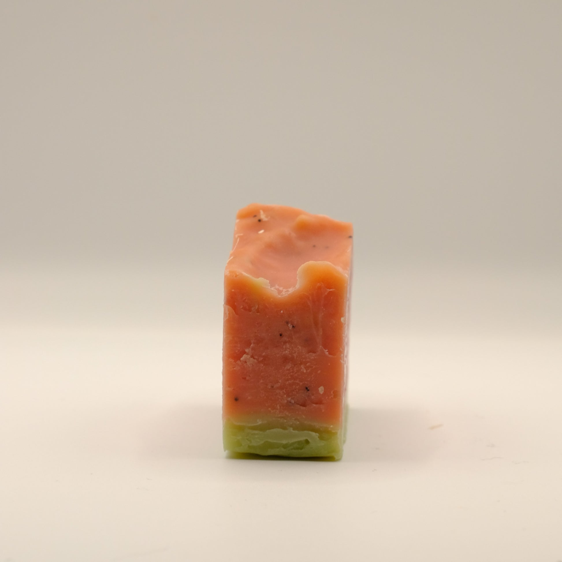 Rectangular bar of soap with a gradient from red to green on a beige background