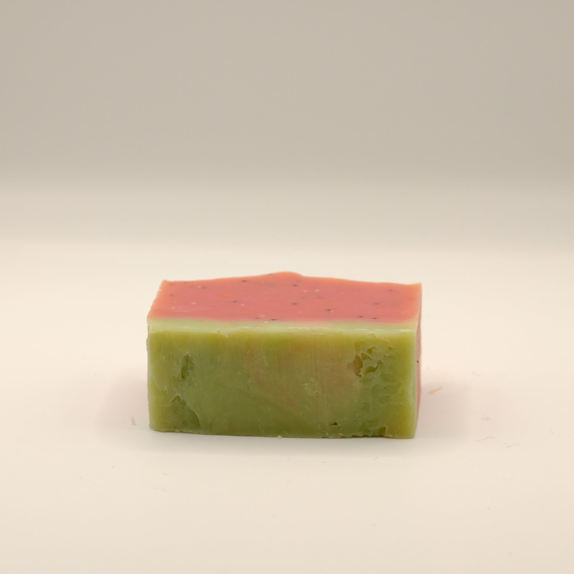 Two-tone green and pink soap bar on a beige background