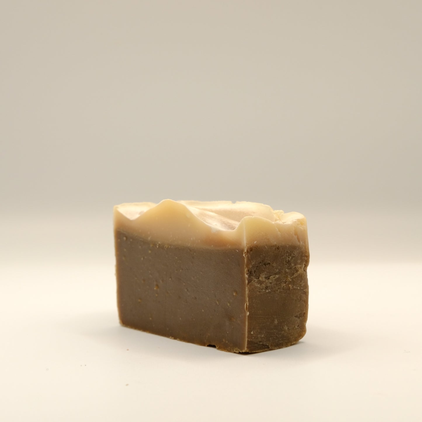 Bar of soap with a beige top and brown bottom on a light gray background
