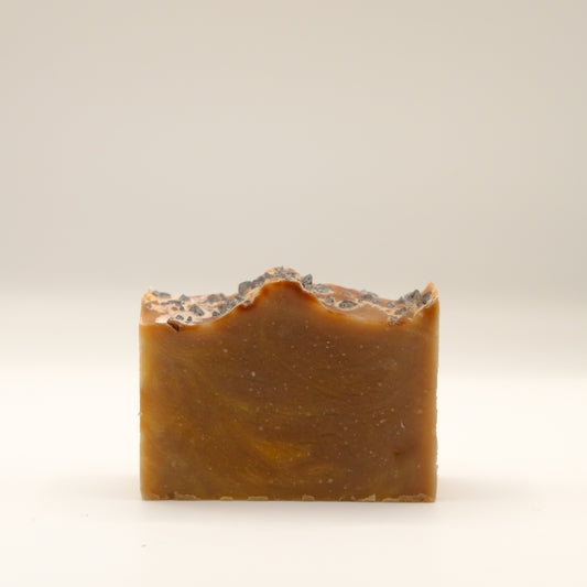Brown bar of soap with a textured surface on a light beige background