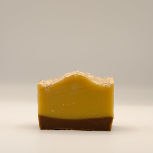 Two-tone soap bar with a brown bottom and yellow top on a light gray background