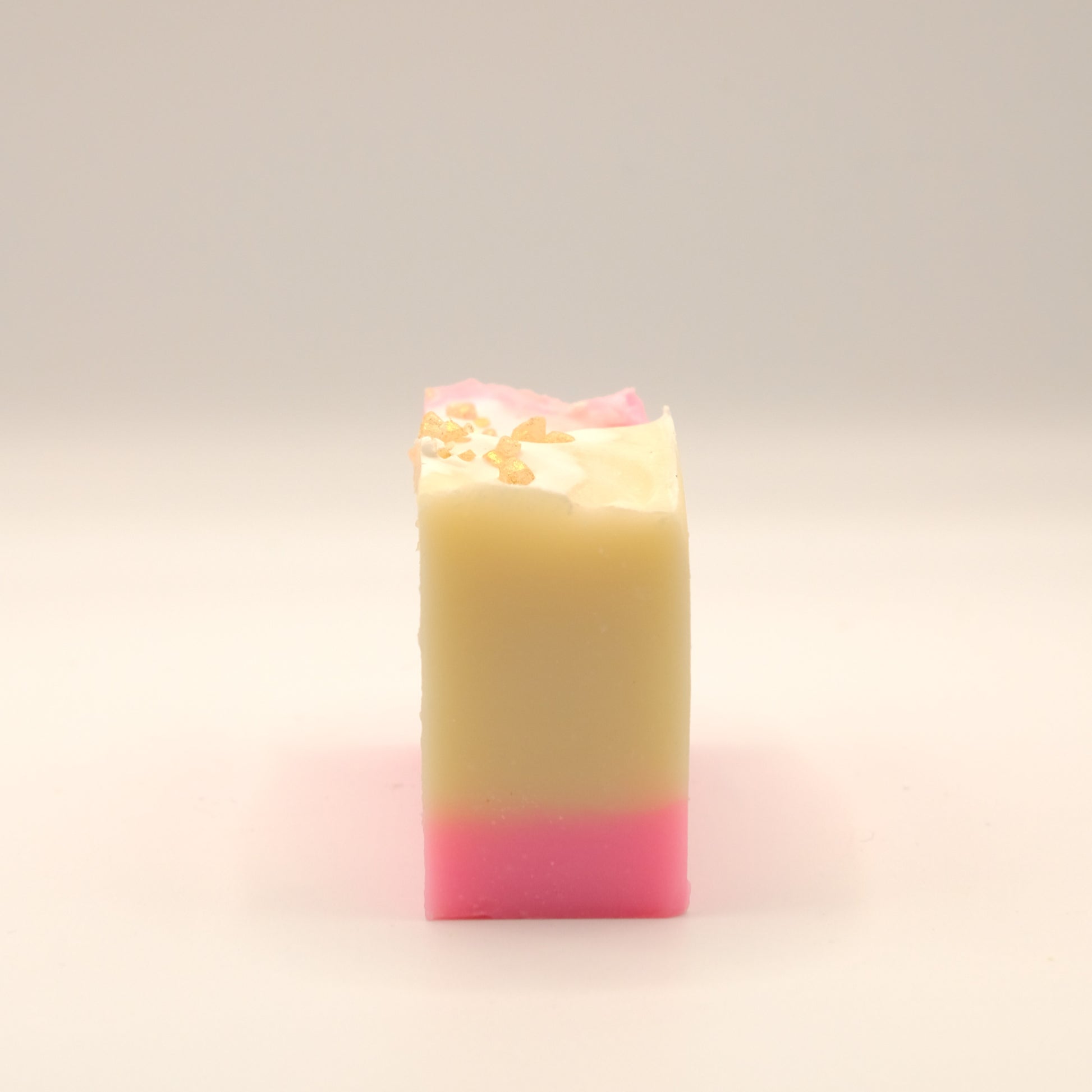 Beige and pink layered bar of soap with gold speckles on a light background.