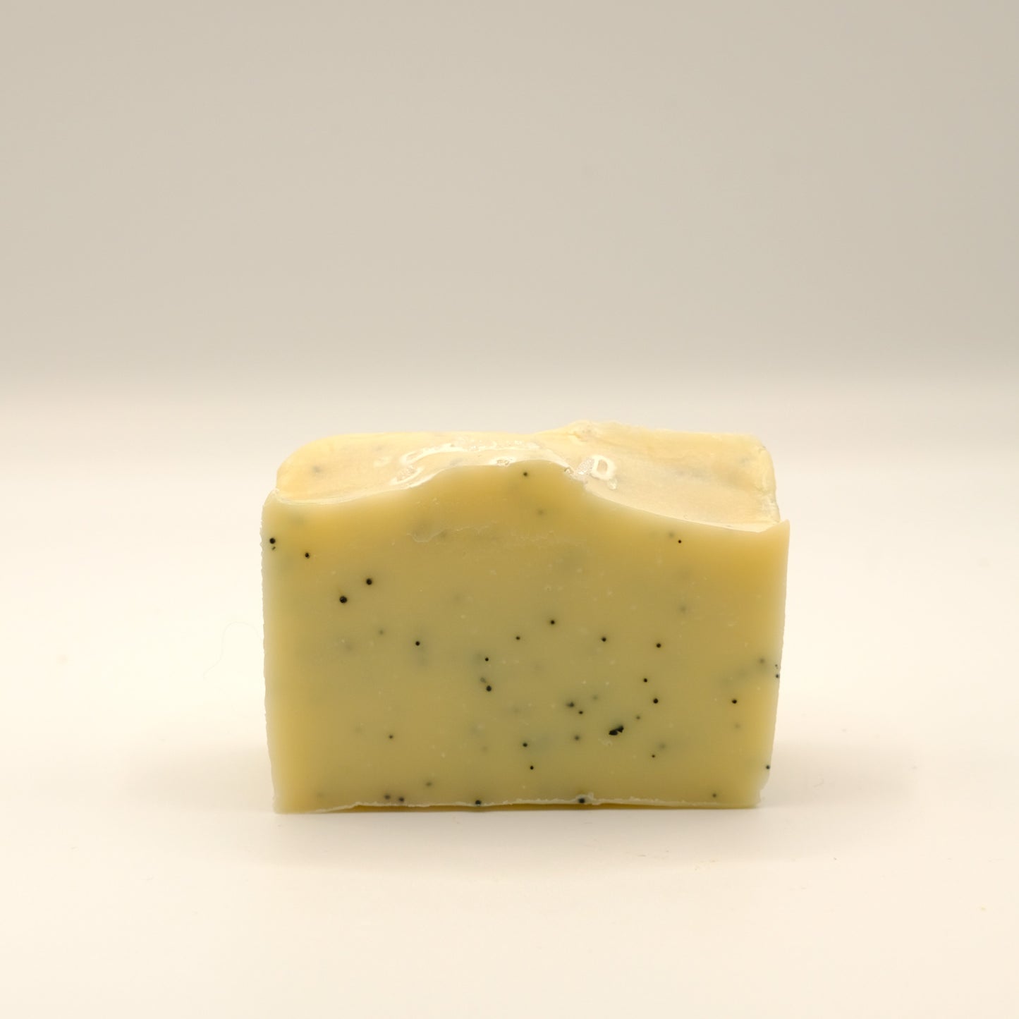 Yellow bar of soap with specks on a light background