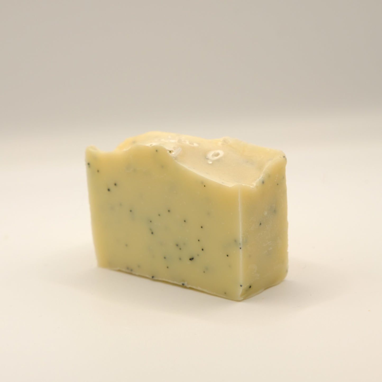 Yellow bar of soap with specks on a light background