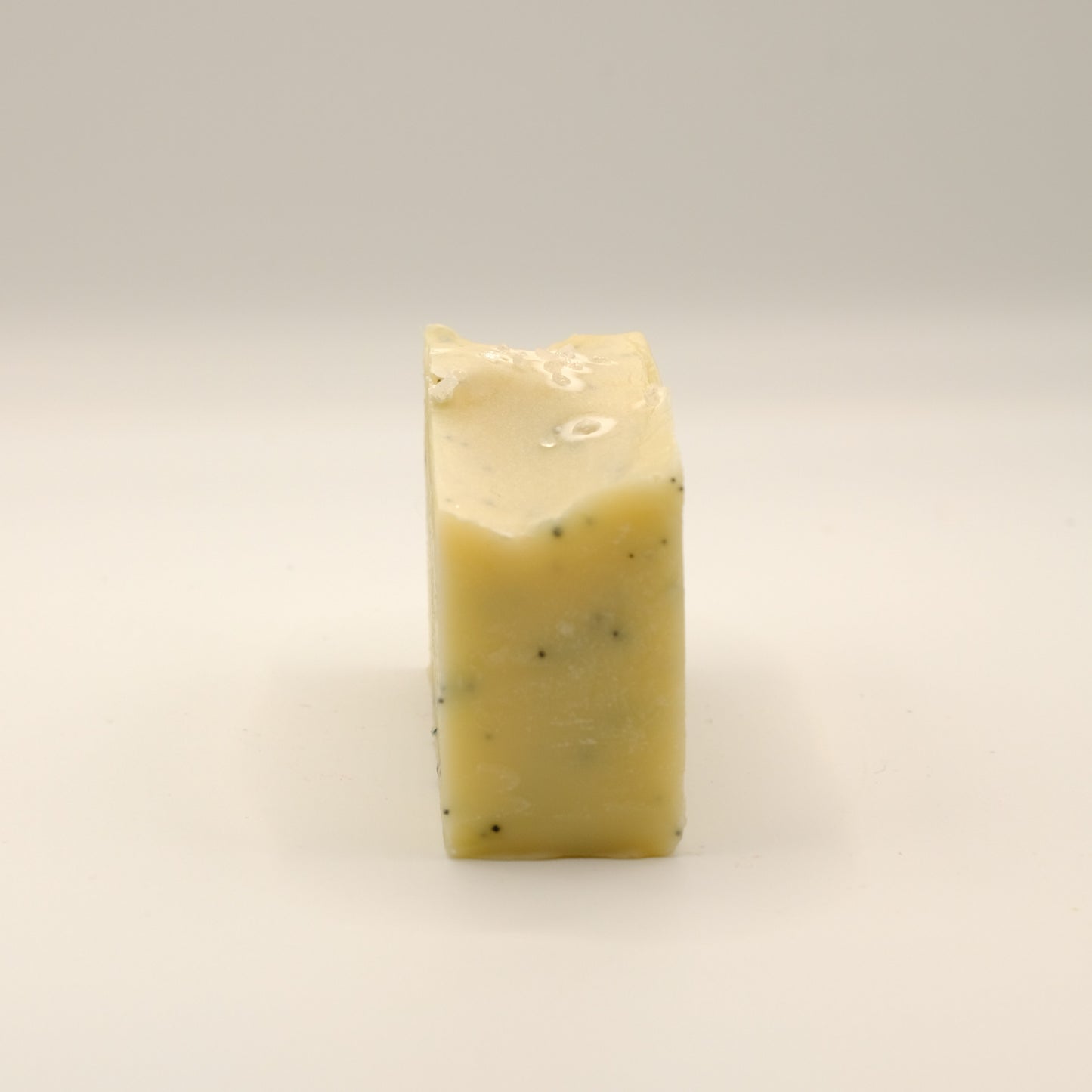 Yellow, rectangular block of soap with specks on a light background