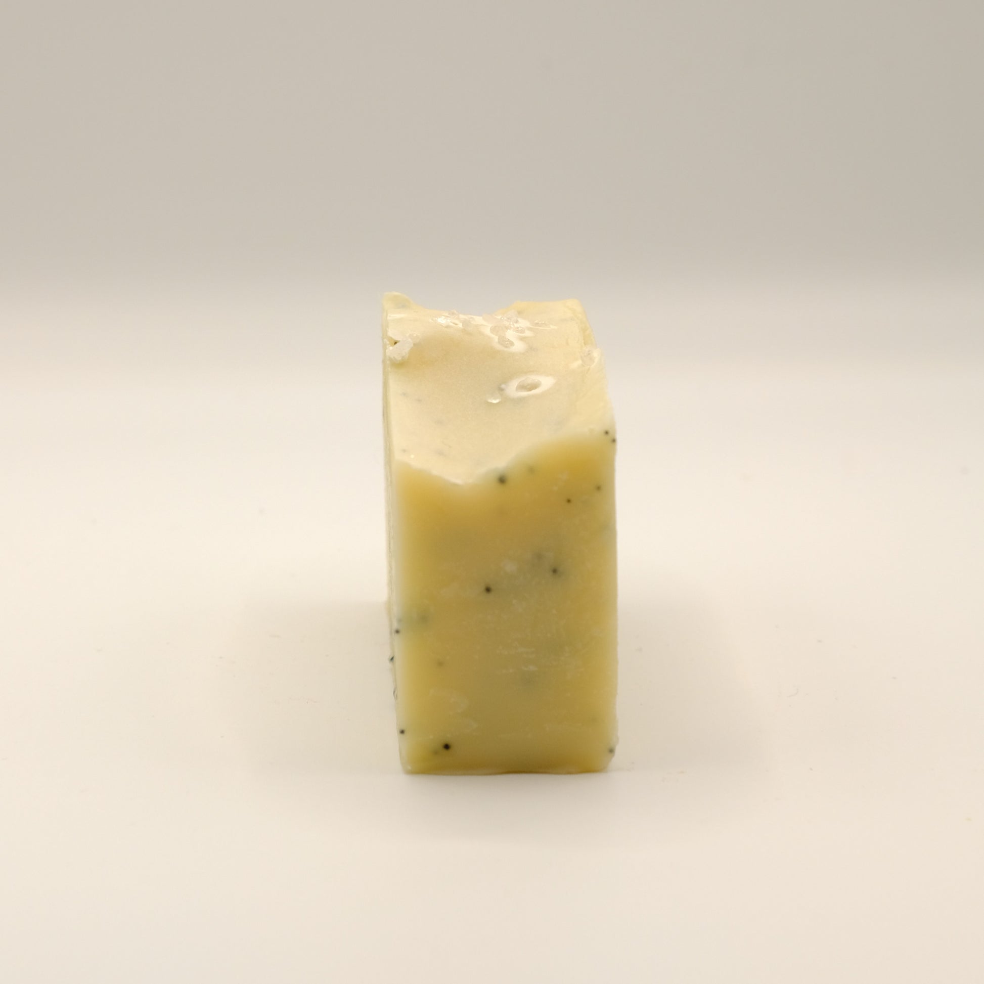 Yellow, rectangular block of soap with specks on a light background