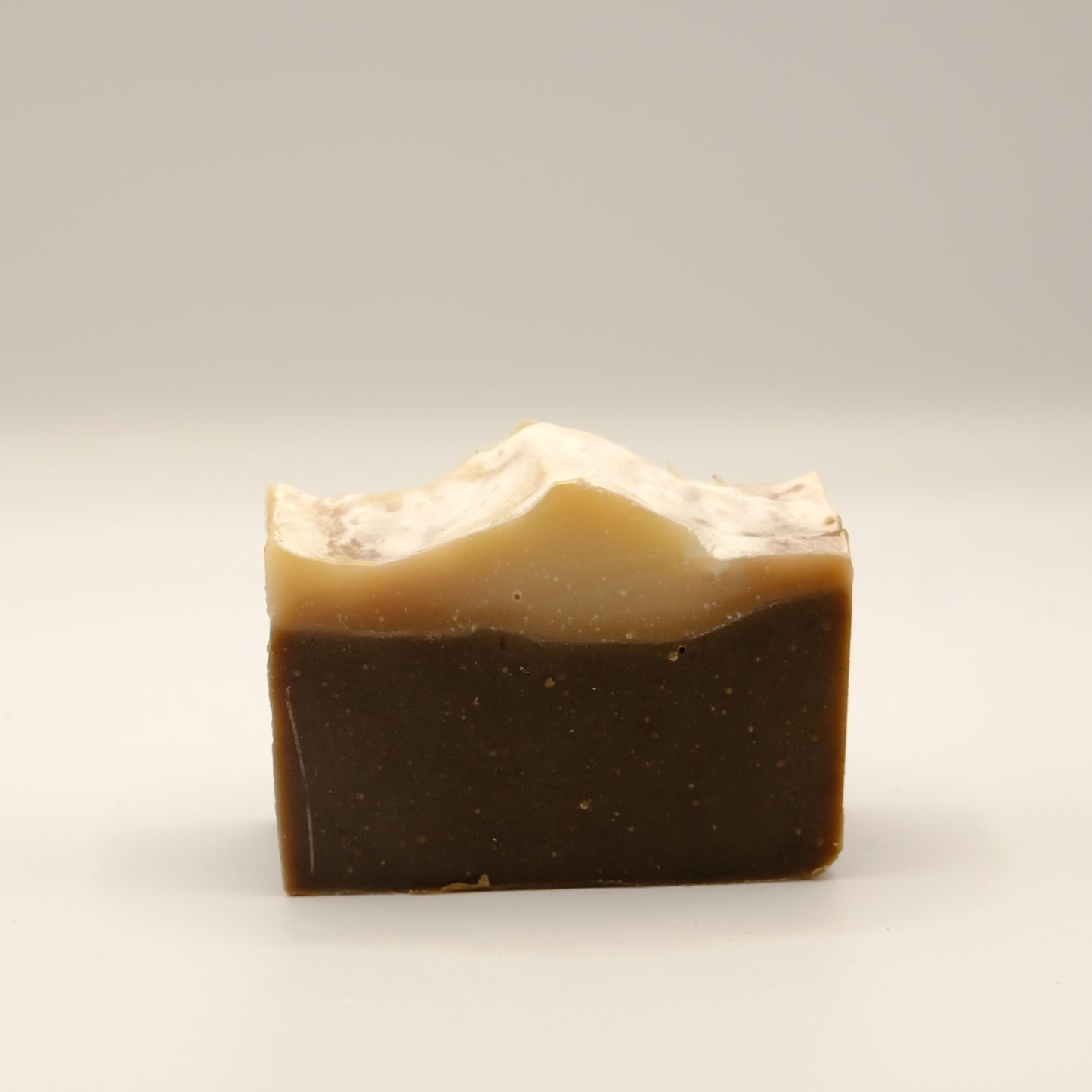Two-layered soap bar with a dark bottom and light top on a white background