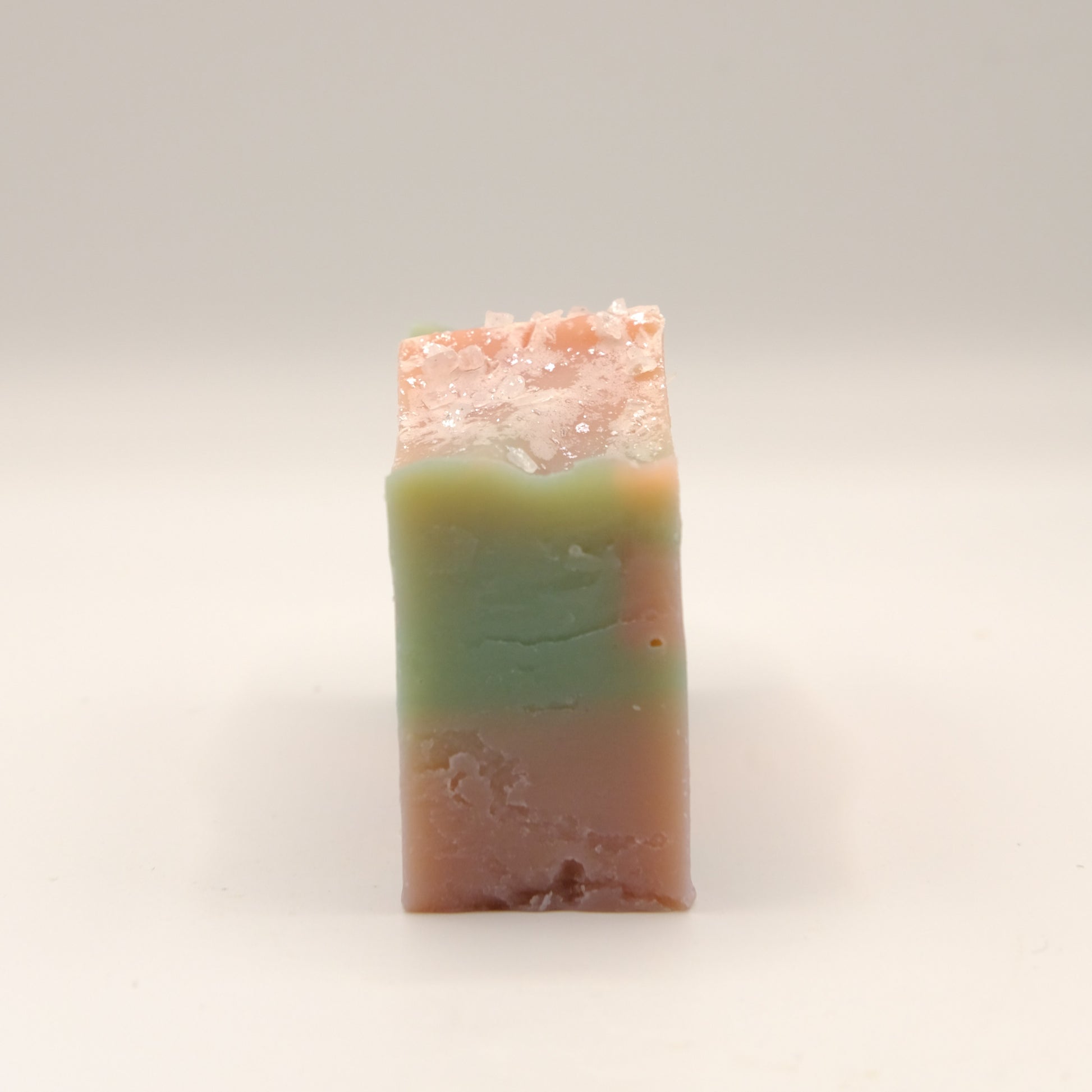 Bar of soap with a gradient from green to pink on a light background