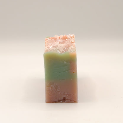 Bar of soap with a gradient from green to pink on a light background
