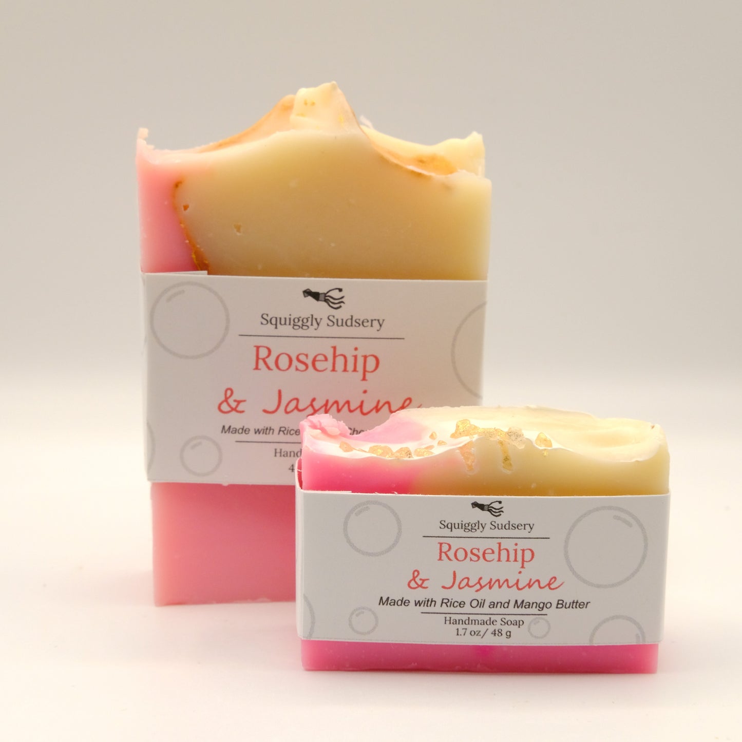 Two bars of 'Rosehip & Jasmine' soap with packaging on a light background
