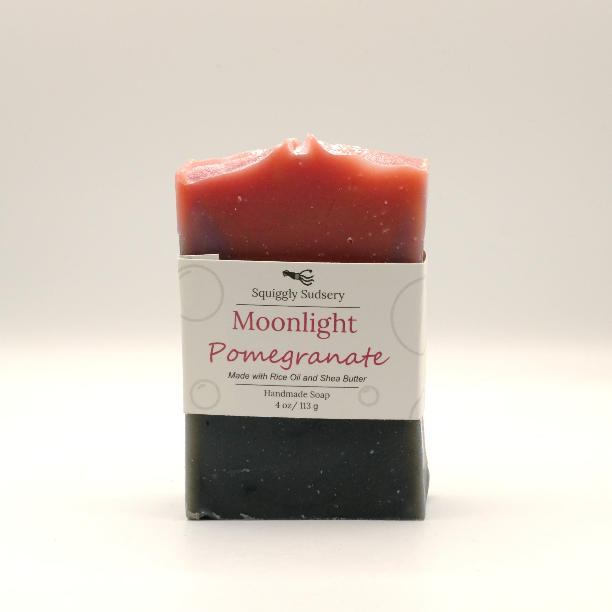 Red and black bar of soap labeled 'Moonlight Pomegranate' with a white background