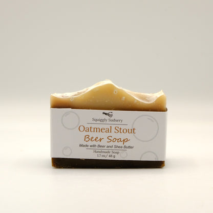 Beige and dark brown bar of oatmeal stout beer soap with a white label on a light gray background