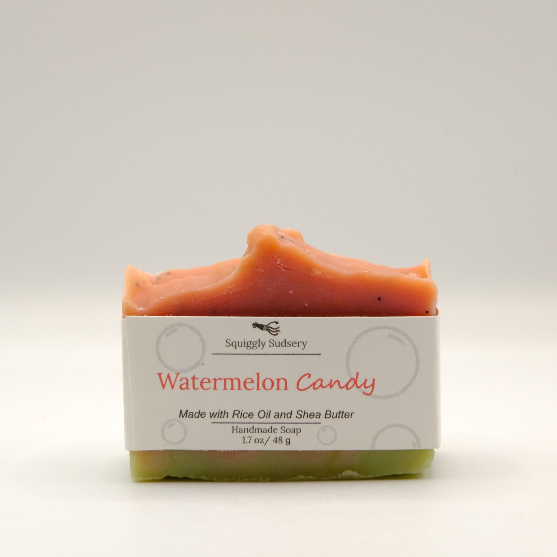 Bar of watermelon candy soap with a white label on a light background