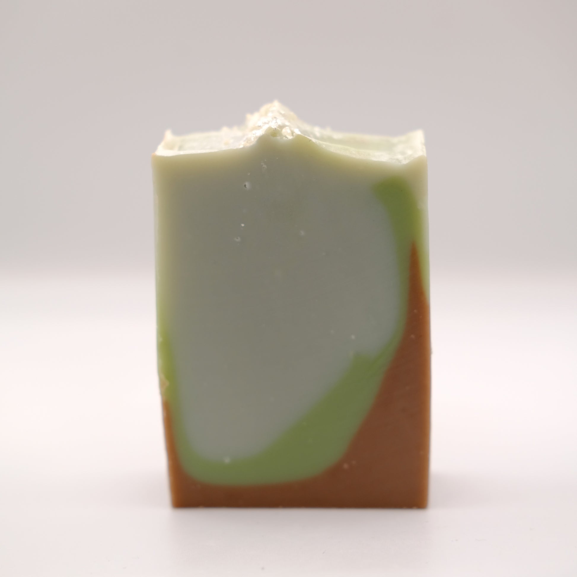 Bar of soap with green and brown gradient on a white background